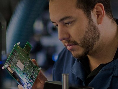 Man in lab coat inspecting FPGA board